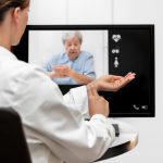 Doctor and senior woman taking pulse together via remote care